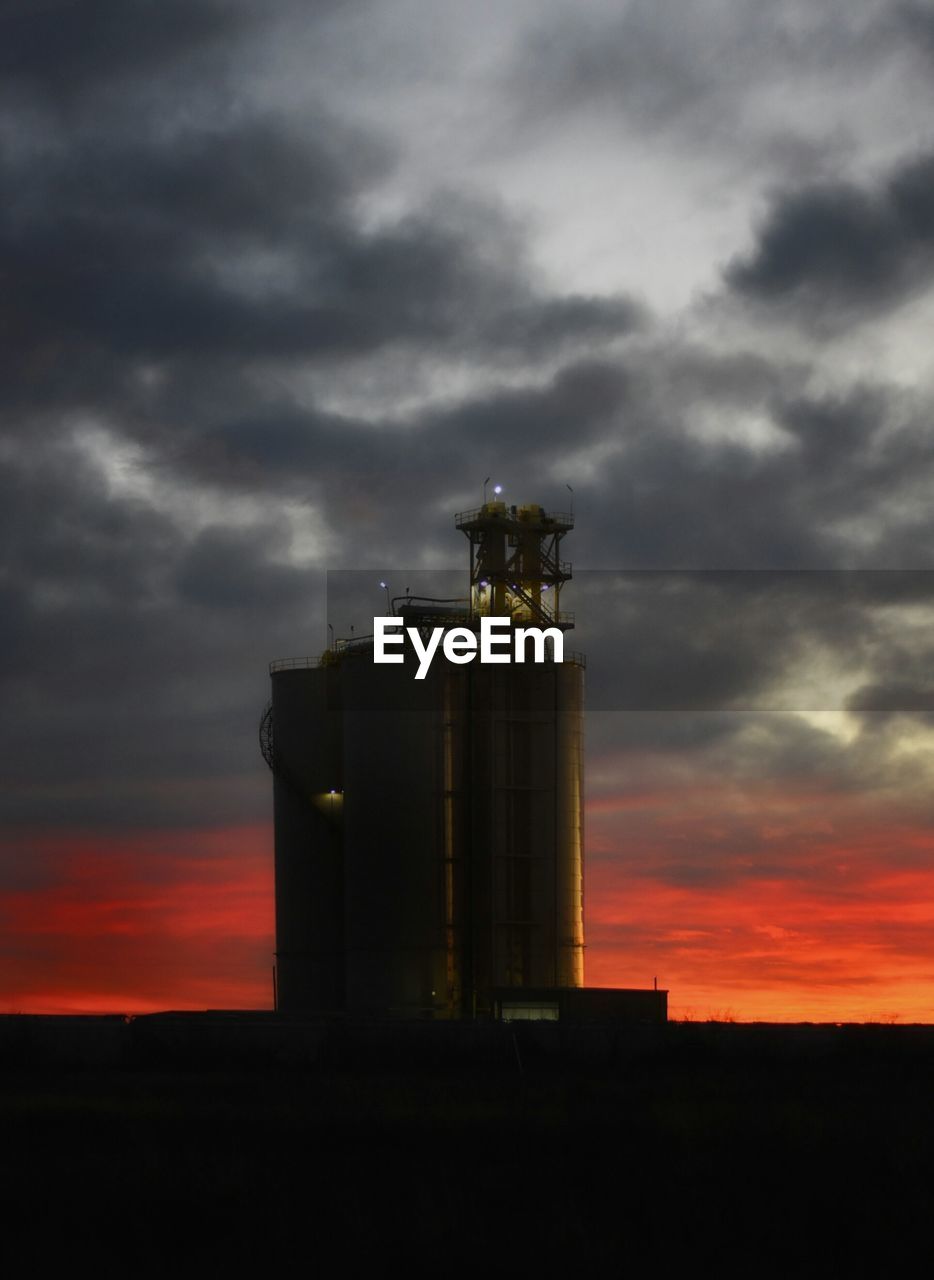 FACTORY AGAINST CLOUDY SKY AT SUNSET