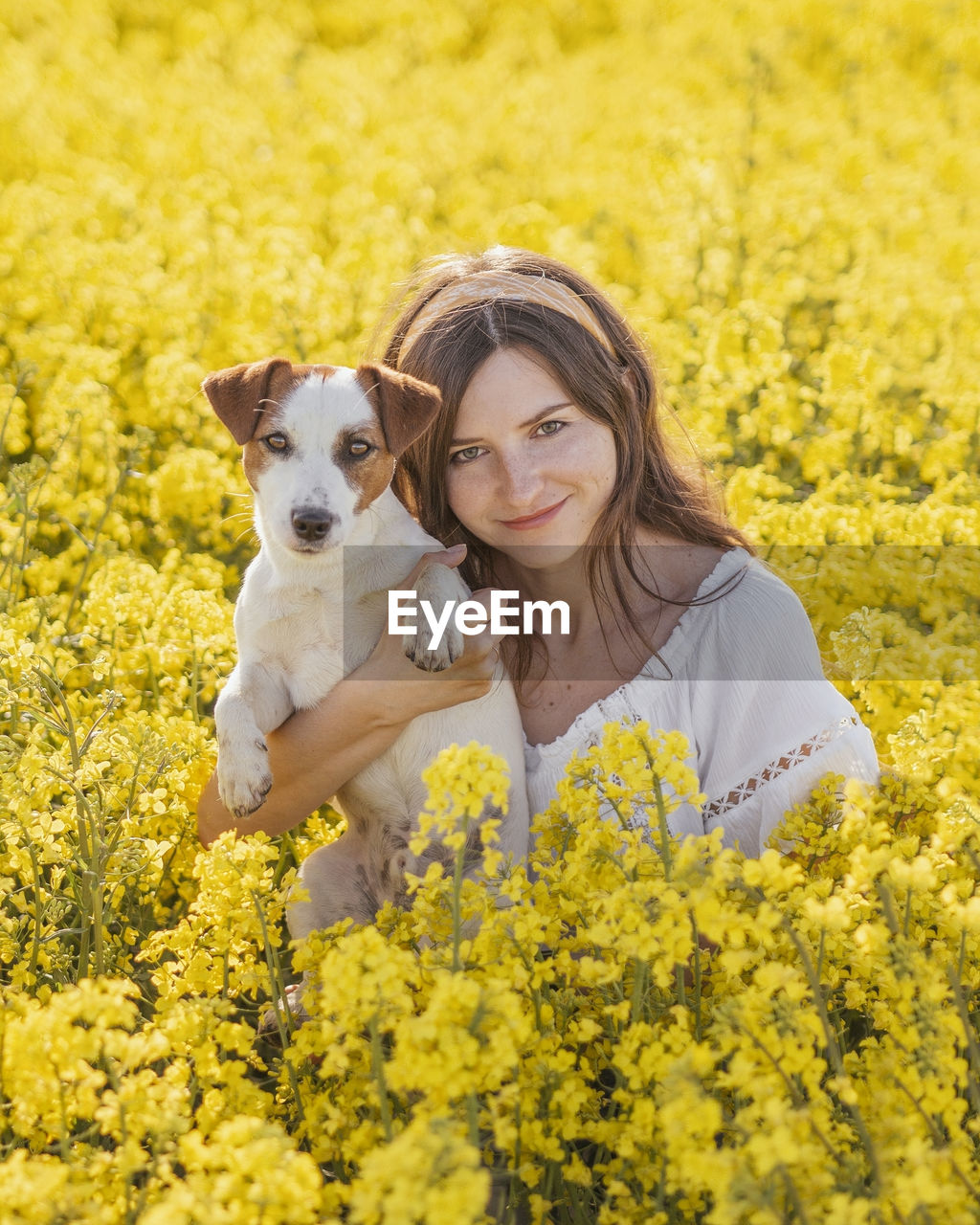 Beautiful woman with dog amidst yellow flowers on field