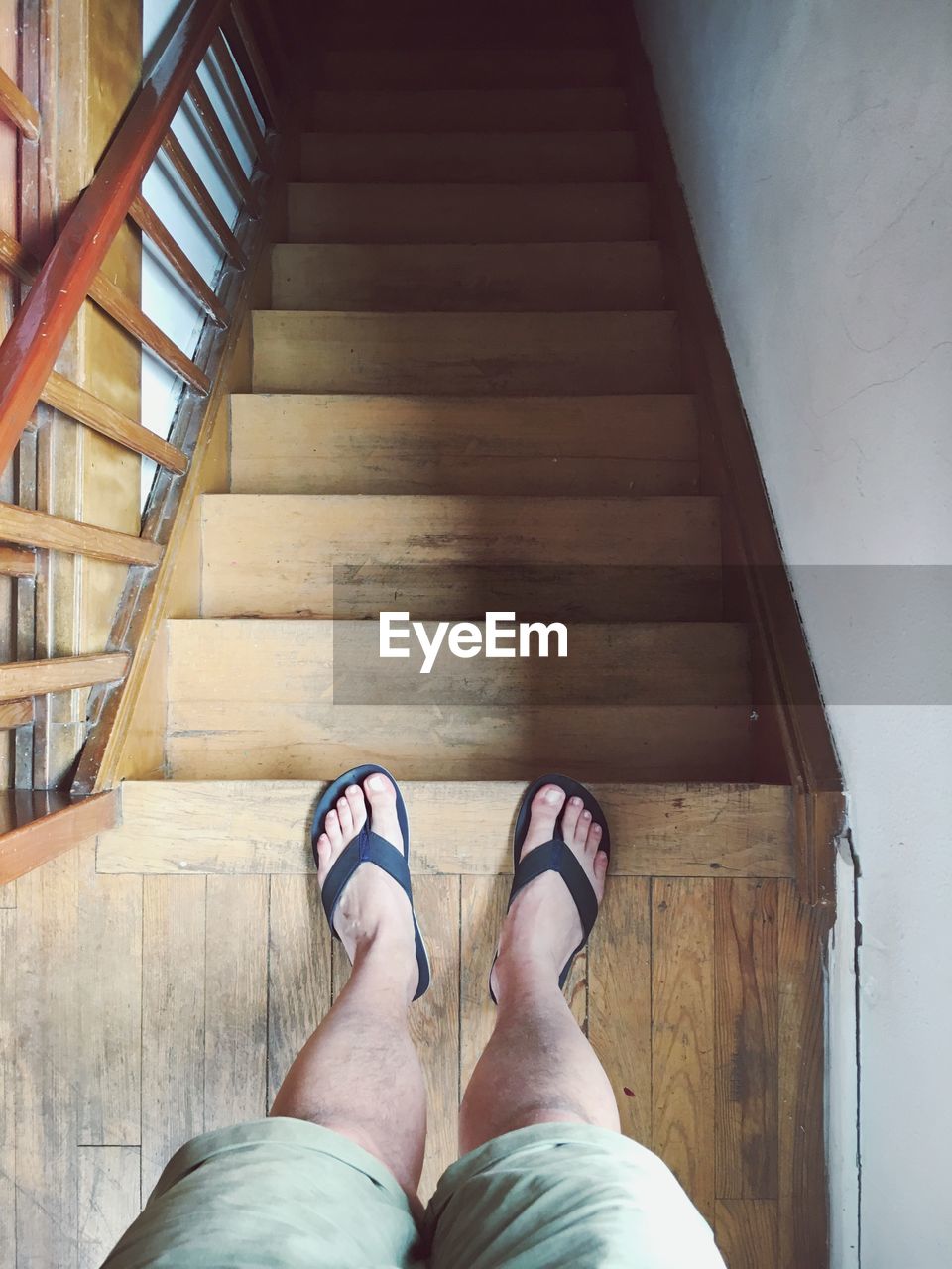 Low section of man standing on wooden steps at home