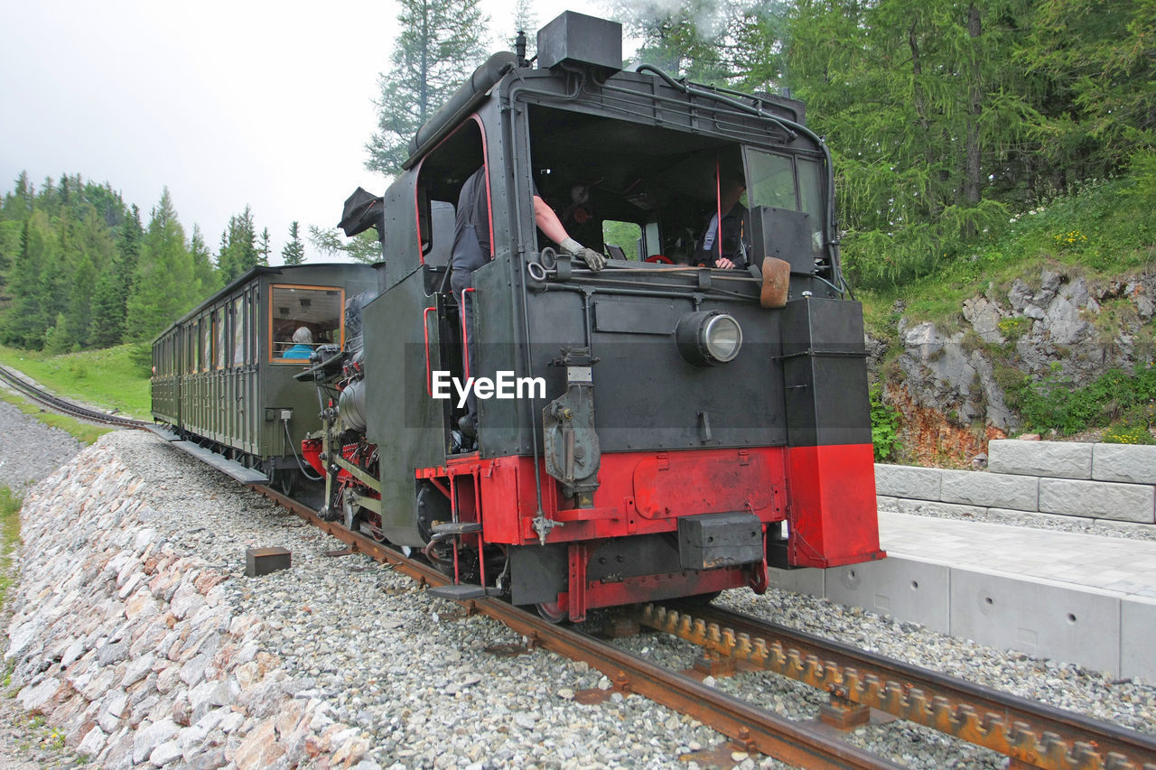 Engineers in steam train at railroad station platform