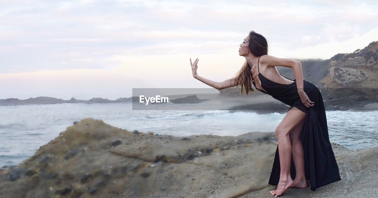 Woman dancing on rock formation at beach