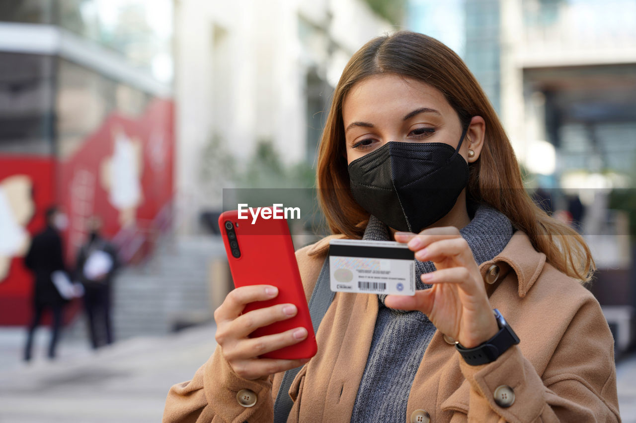 Close-up image of young woman using credit card for purchasing and shopping online on mobile phone