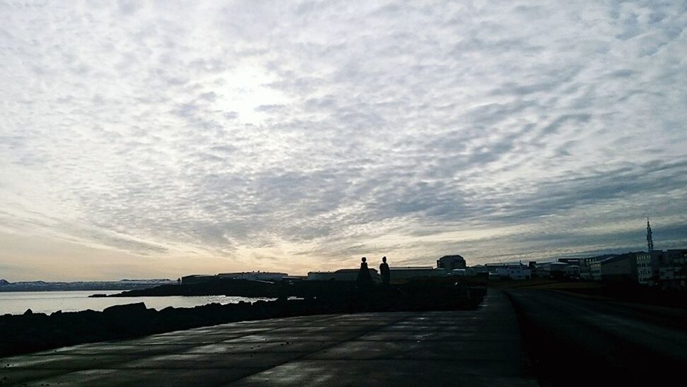 Cloudy sky over sidewalk by sea