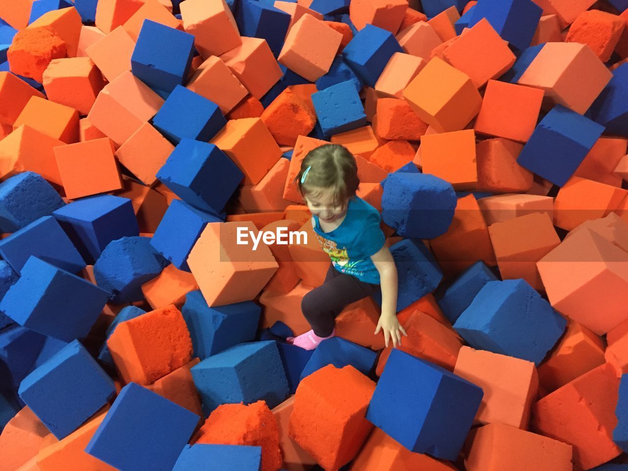 High angle view of girl playing on cube shape sponge
