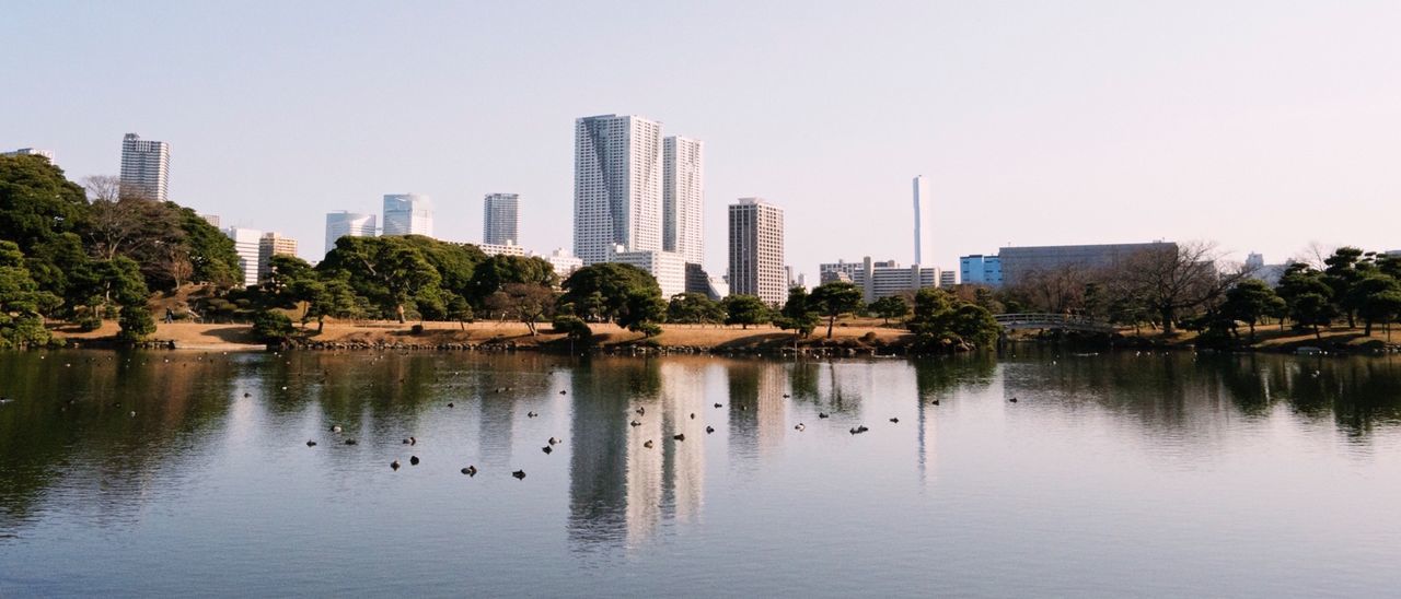 Reflection of buildings in river against clear sky