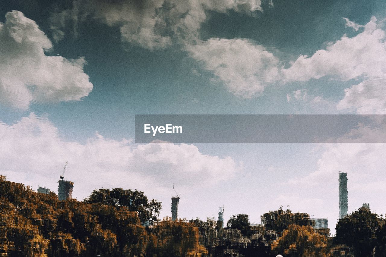 Smoke stack amidst trees against sky