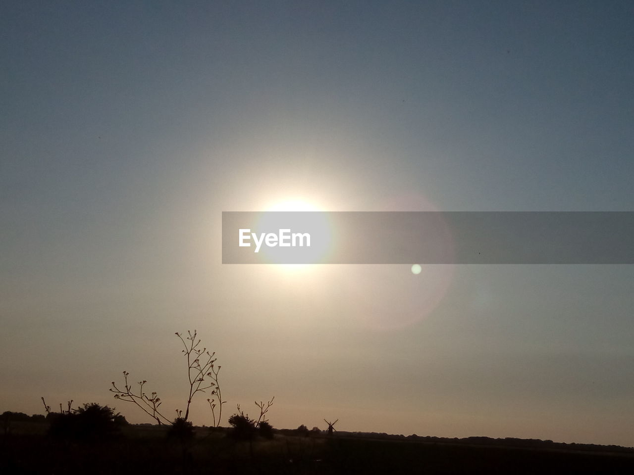 sky, beauty in nature, scenics - nature, tranquil scene, tranquility, silhouette, sun, sunset, sunlight, landscape, nature, idyllic, environment, no people, non-urban scene, field, outdoors, land, circle, plant, lens flare, bright, brightly lit, eclipse