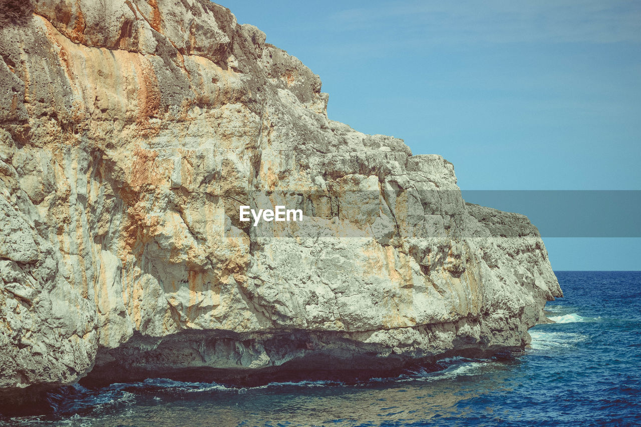 ROCK FORMATIONS ON SEA SHORE AGAINST SKY