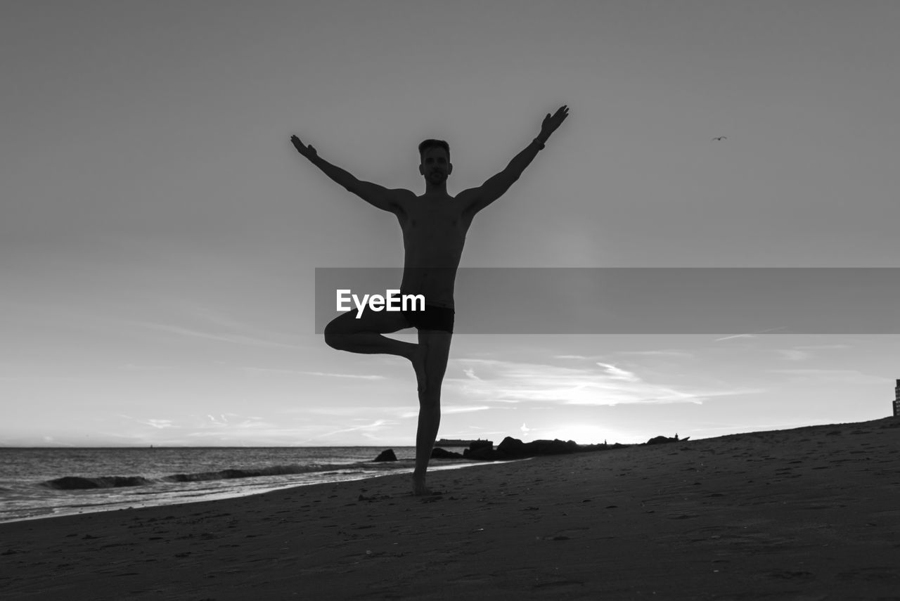 Full length of man exercising at beach