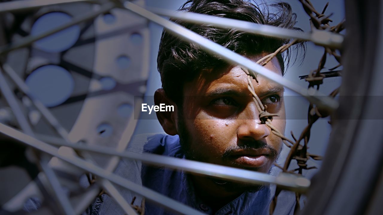 Close-up of thoughtful young man looking away by wheel