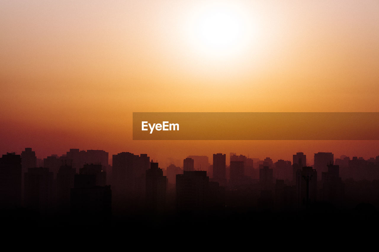 SILHOUETTE BUILDINGS IN CITY AGAINST ORANGE SKY