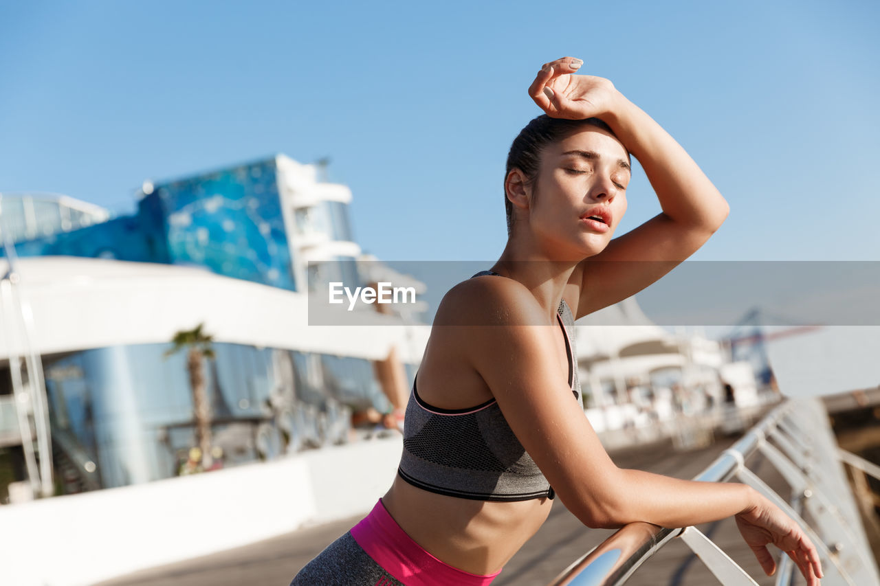 Woman leaning on railing against sky