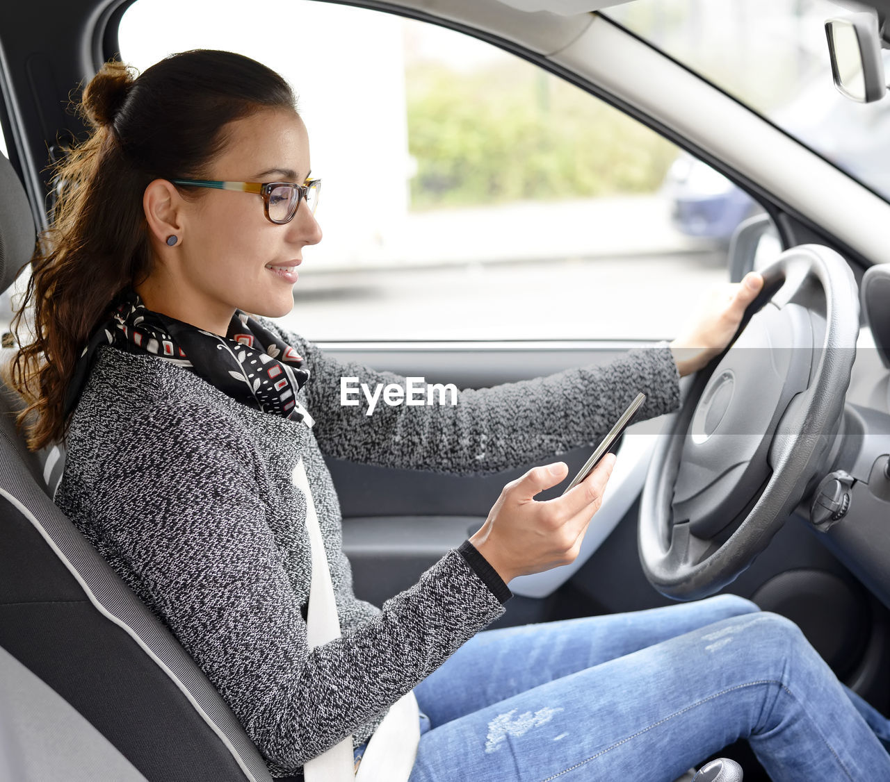 Side view of young woman using phone while sitting in car