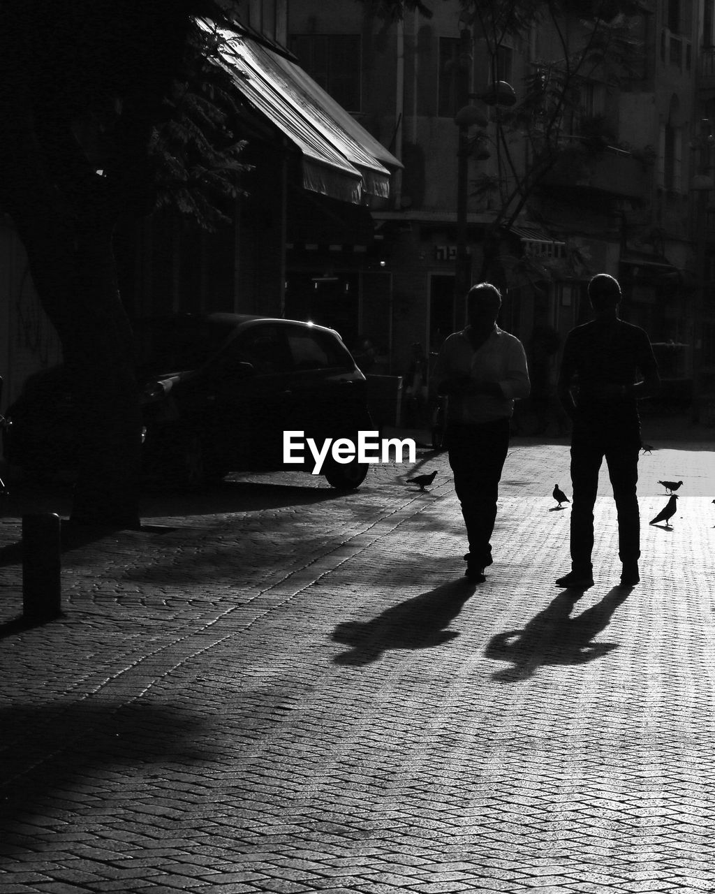 REAR VIEW OF WOMEN WALKING ON STREET IN CITY