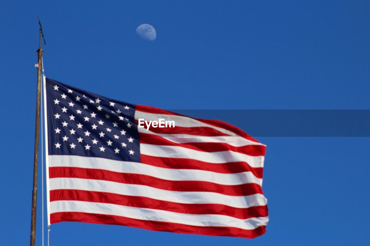 Low angle view of flag against clear blue sky