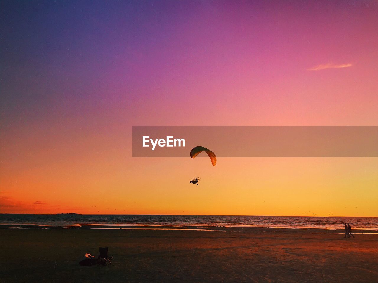 Scenic view of paraglider over sea at sunset 