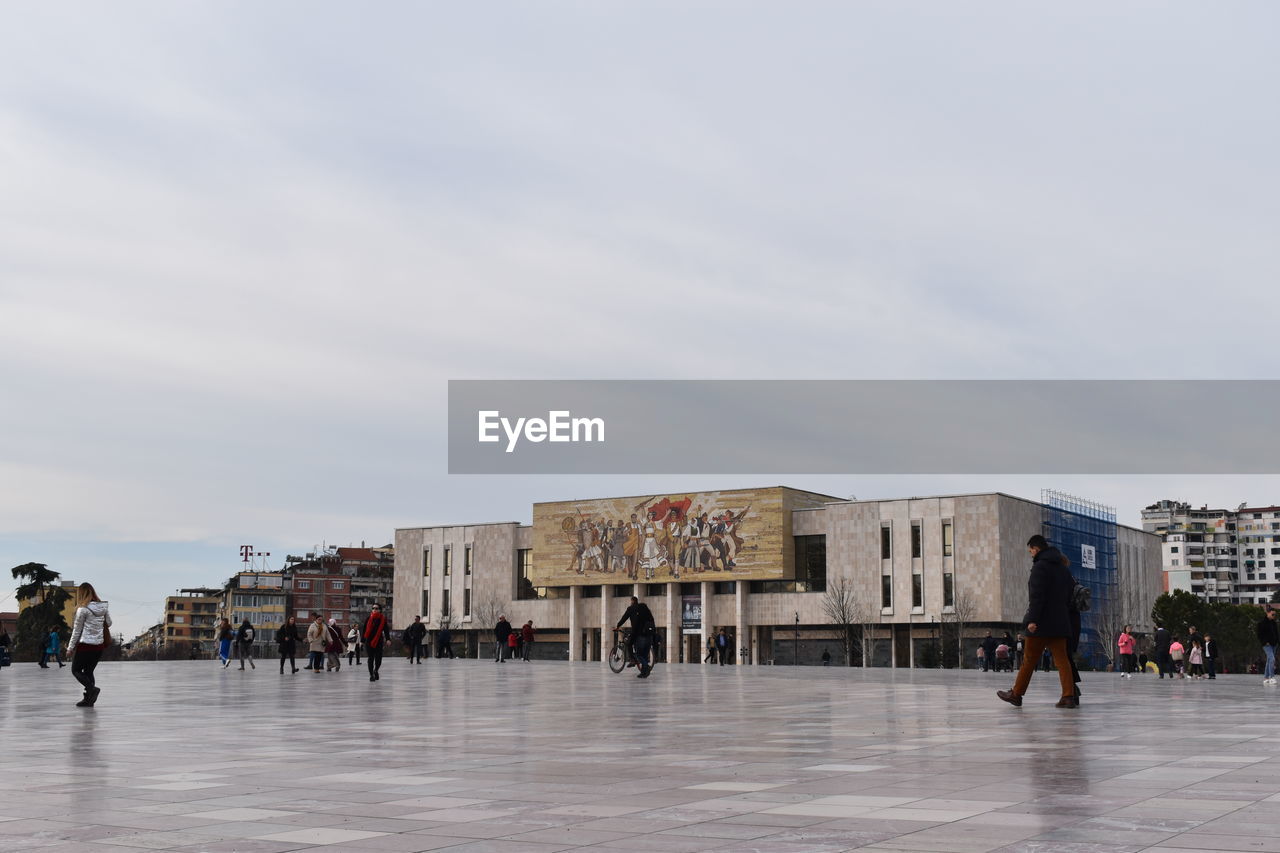 People walking on street against building and sky