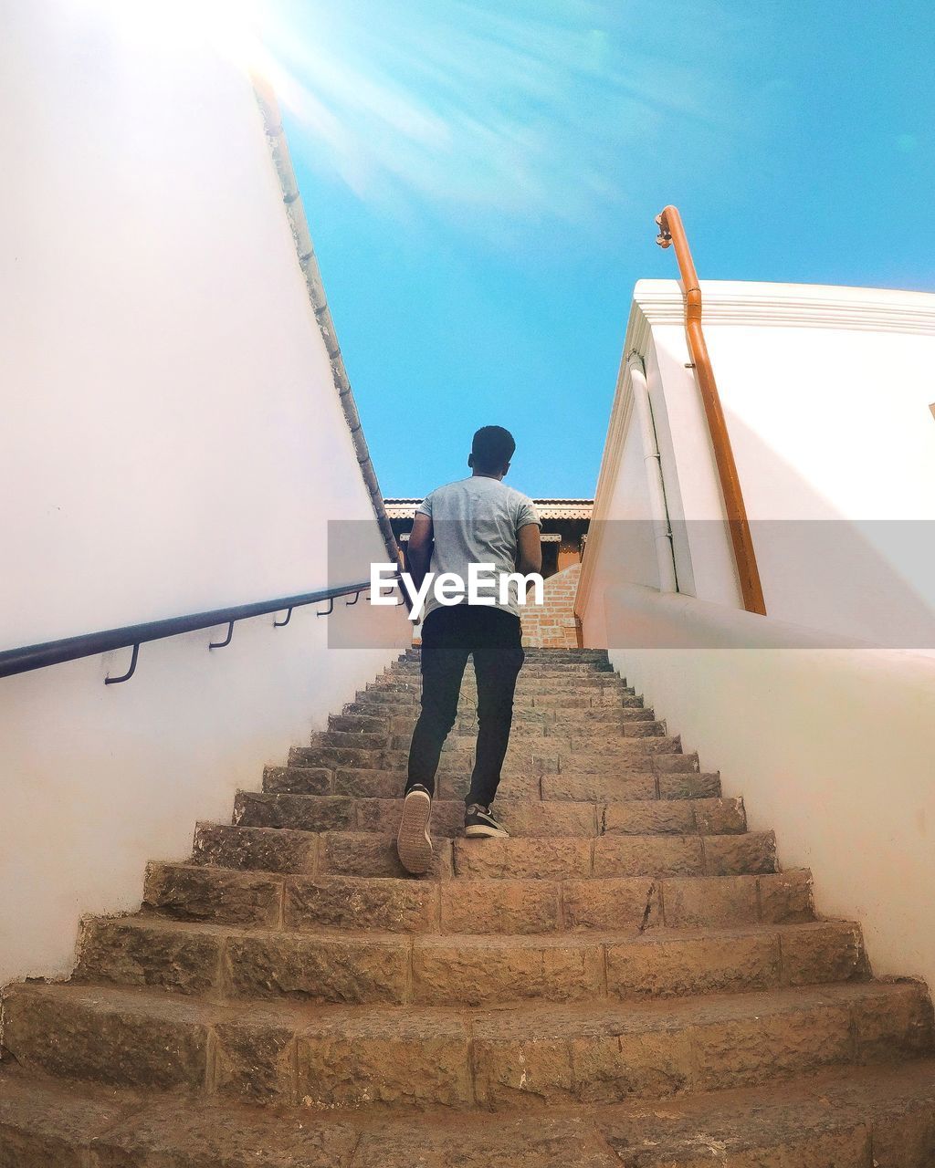 LOW ANGLE VIEW OF MAN STANDING ON STAIRCASE