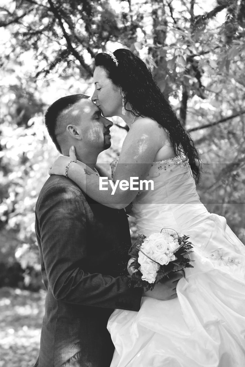 Bride kissing groom on forehead