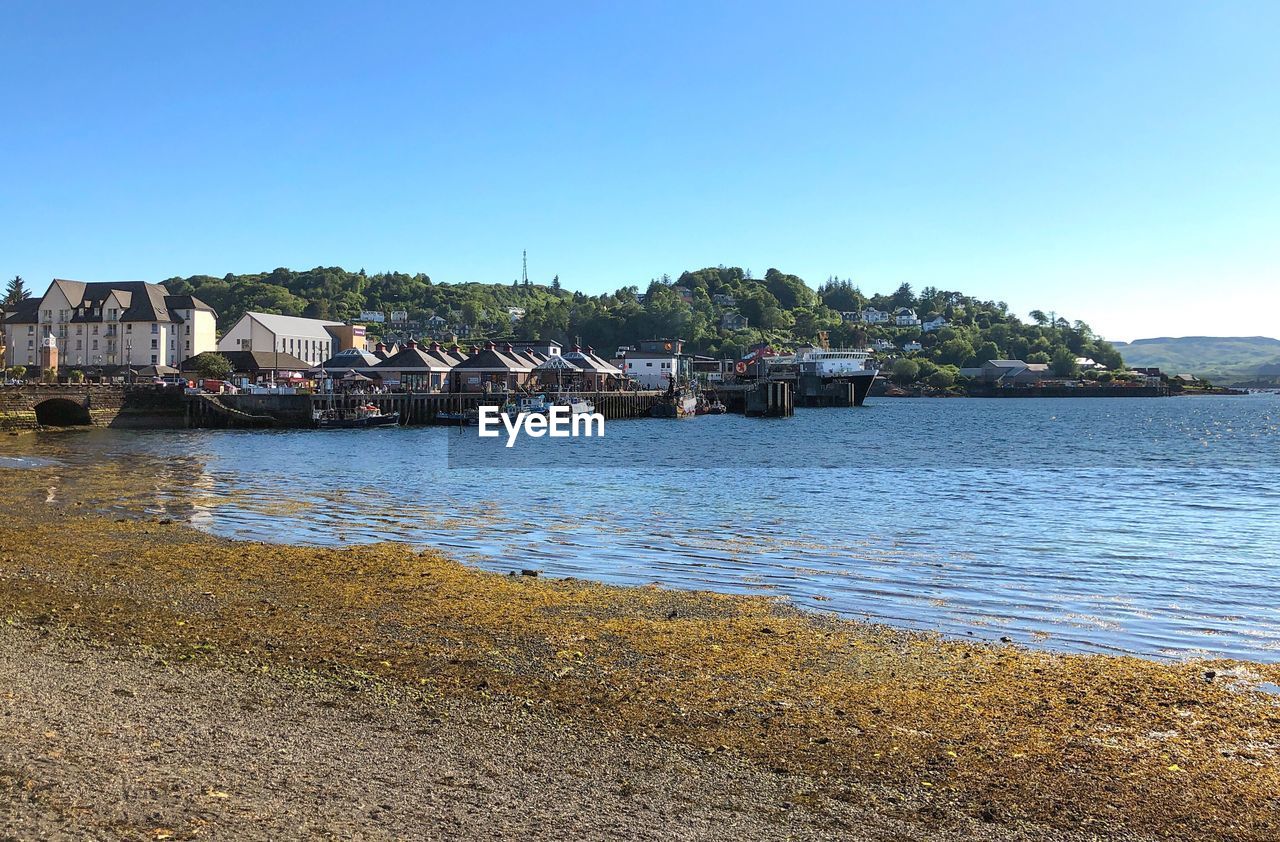 SCENIC VIEW OF RIVER AMIDST BUILDINGS AGAINST CLEAR SKY