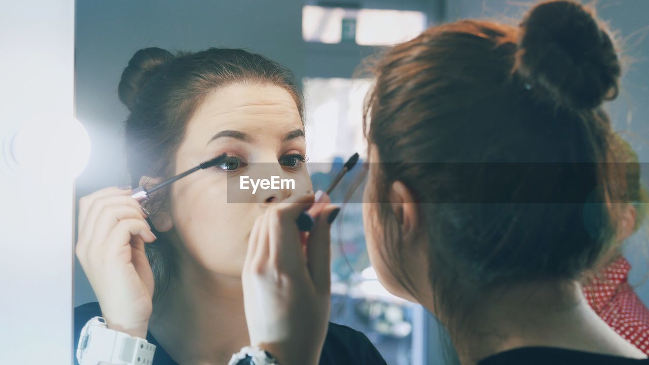 Close-up of a young woman applying mascara