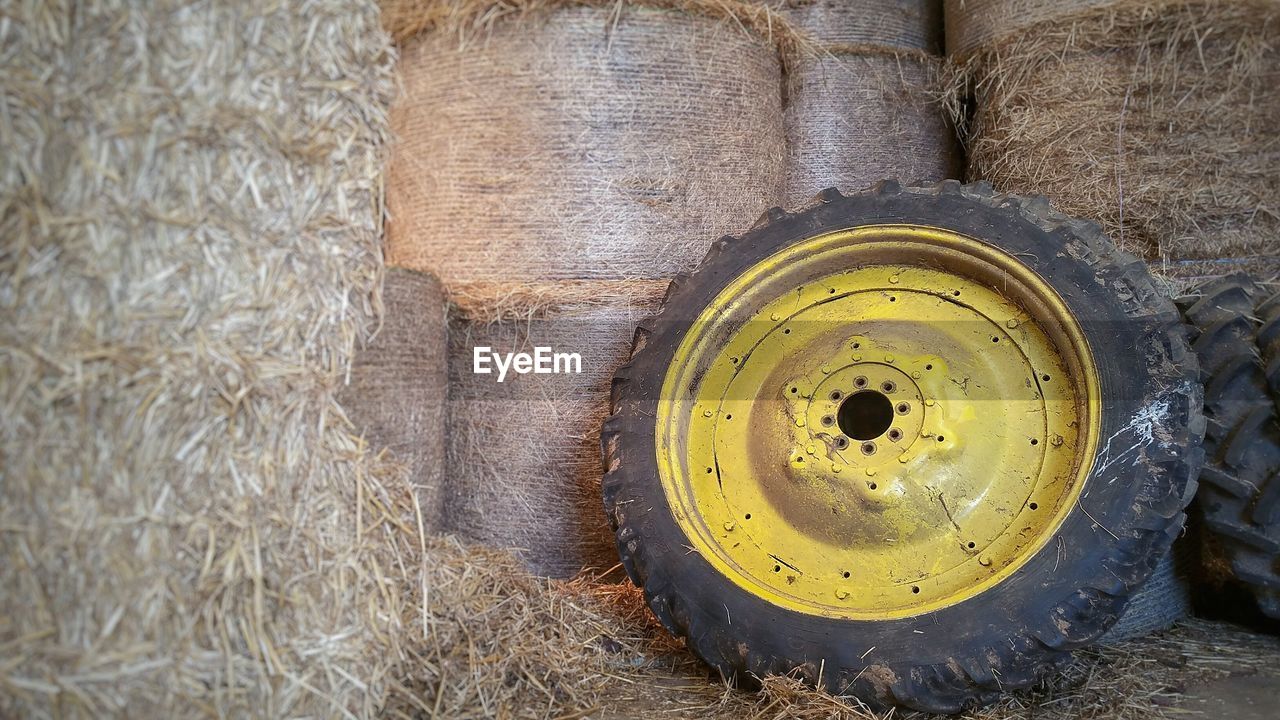 Abandoned tire leaning against hay bales at barn