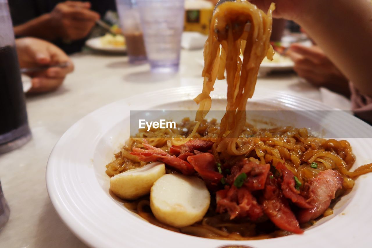 CLOSE-UP OF HAND HOLDING FOOD IN PLATE