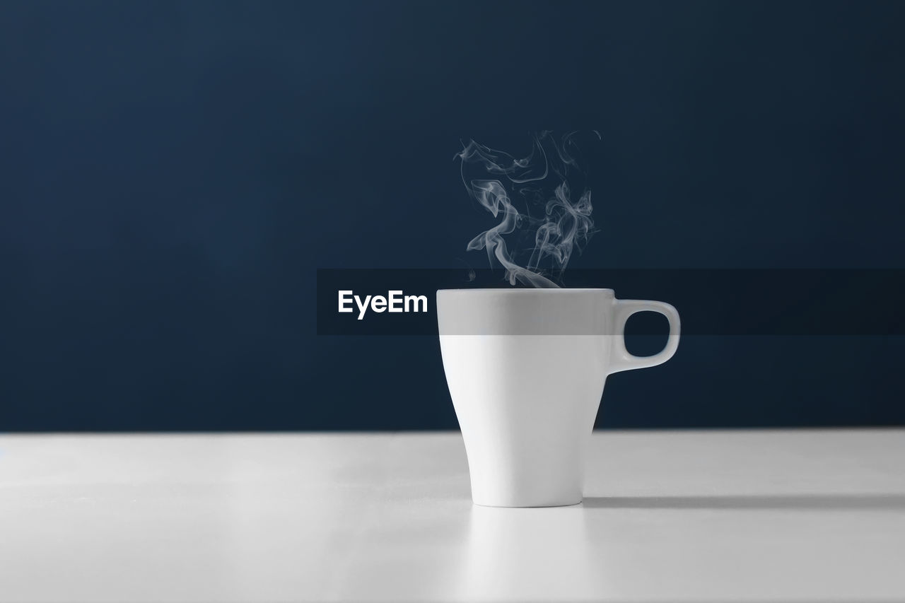 Close-up of coffee cup on table against blue background