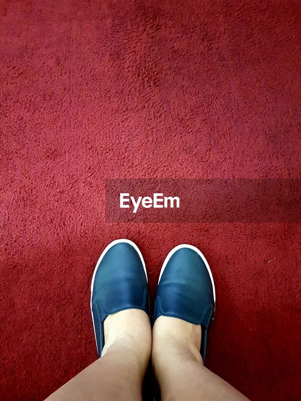 Low section of woman standing on red carpet