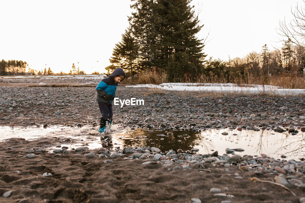 Boy walking playing in stream against sky