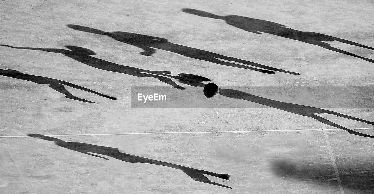 Soccer ball on field with shadows of players