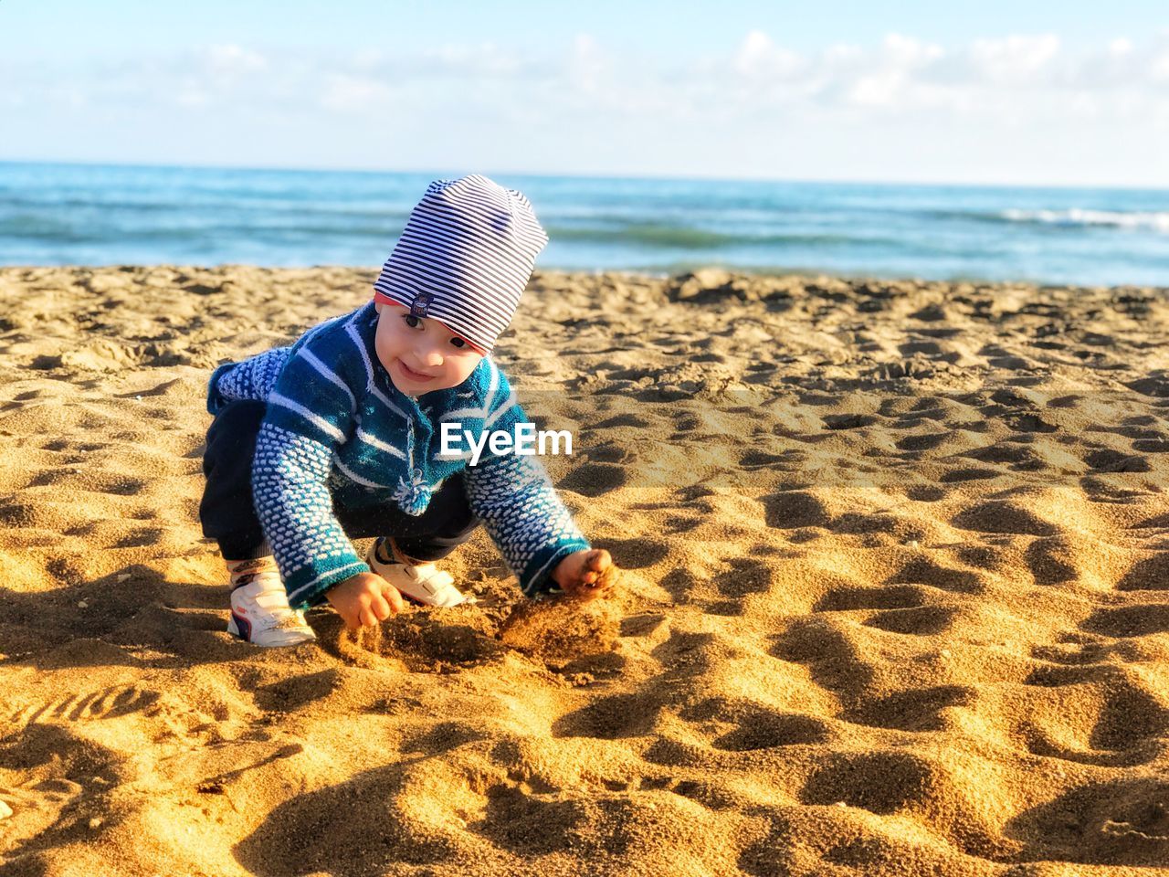 Baby boy playing with sand at beach