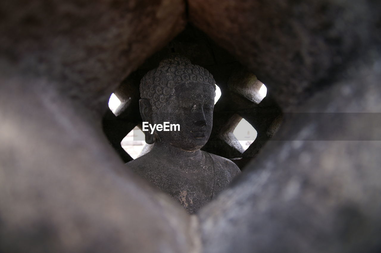 Buddha statue in temple seen through window