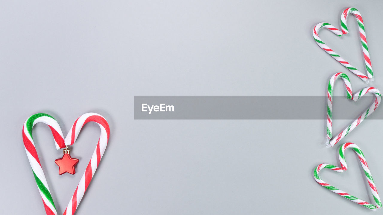 Christmas candy canes in shape of heart on grey