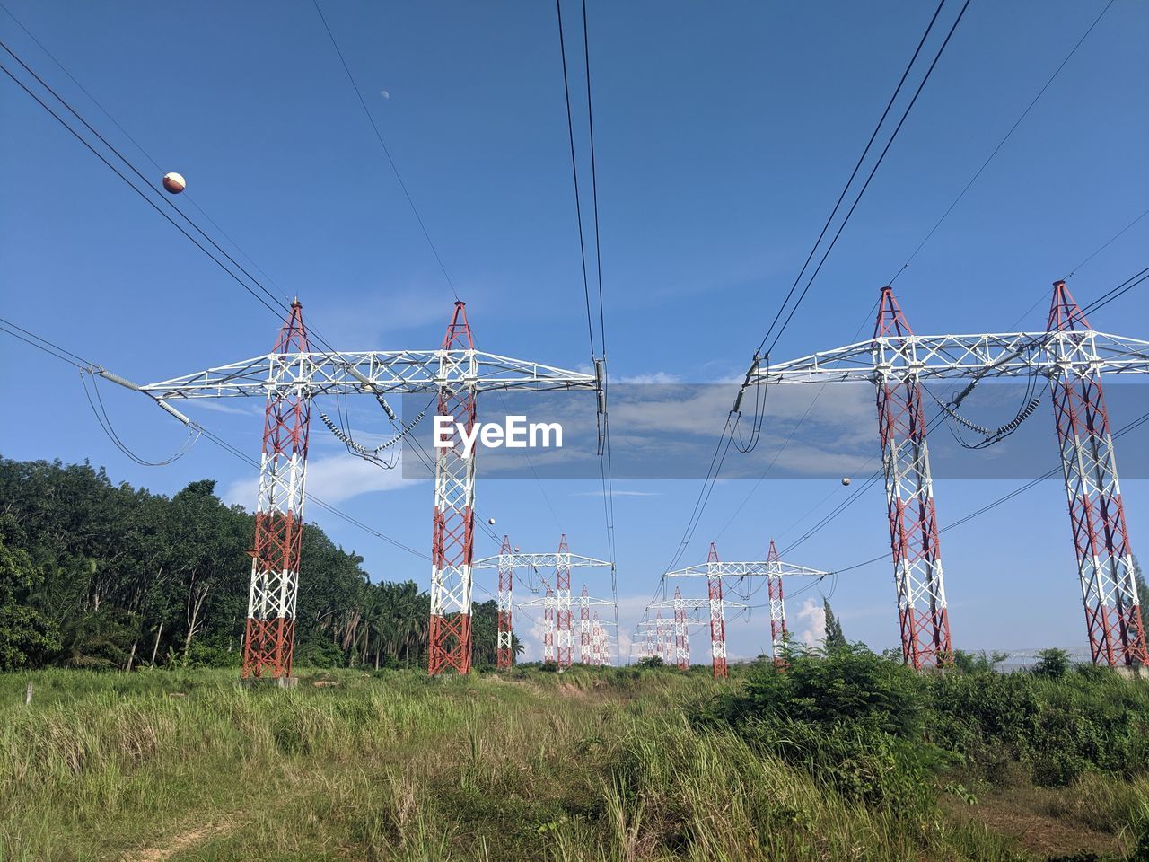 LOW ANGLE VIEW OF ELECTRICITY PYLONS ON FIELD AGAINST SKY