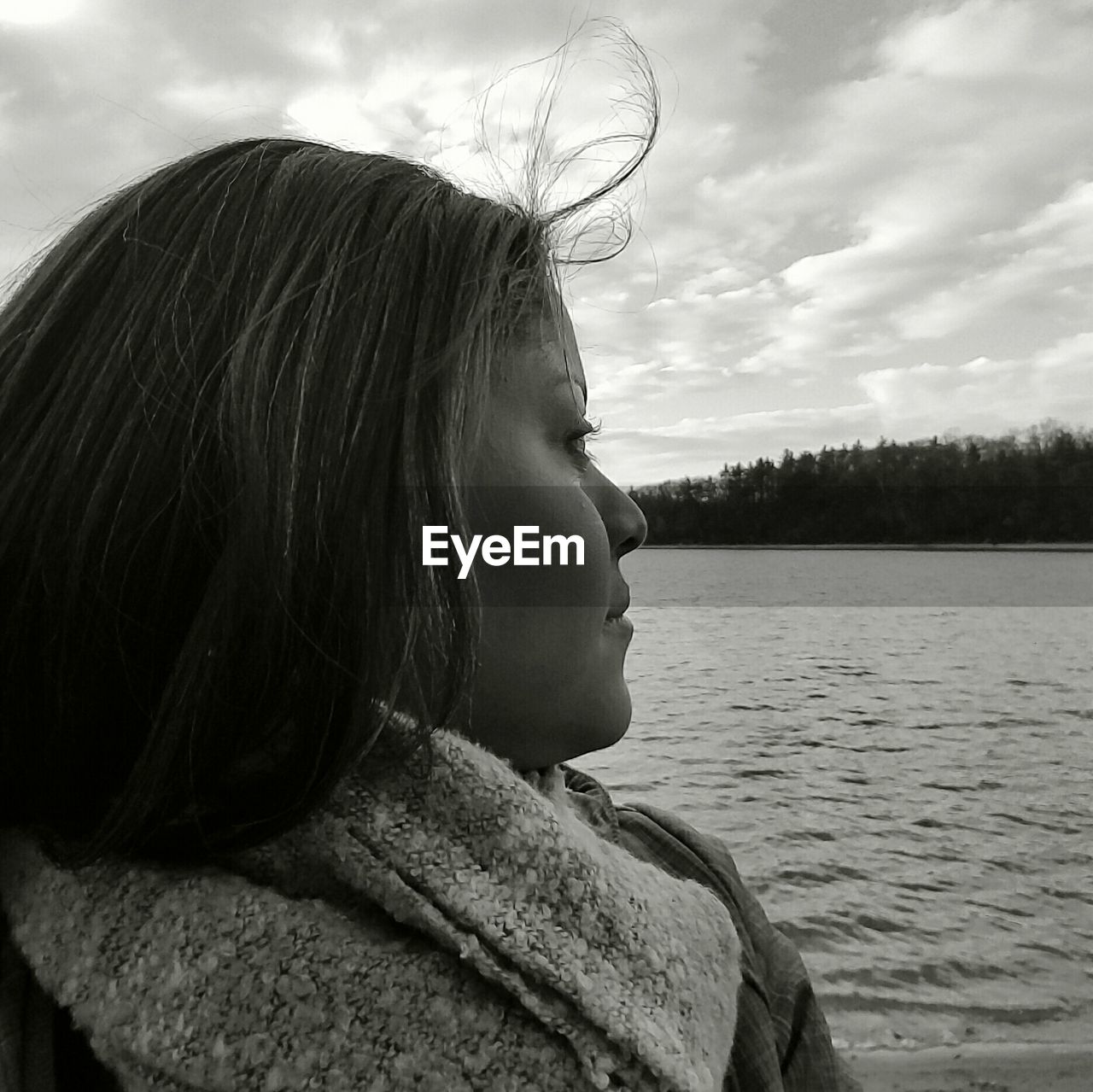 Side view of woman by lake against sky