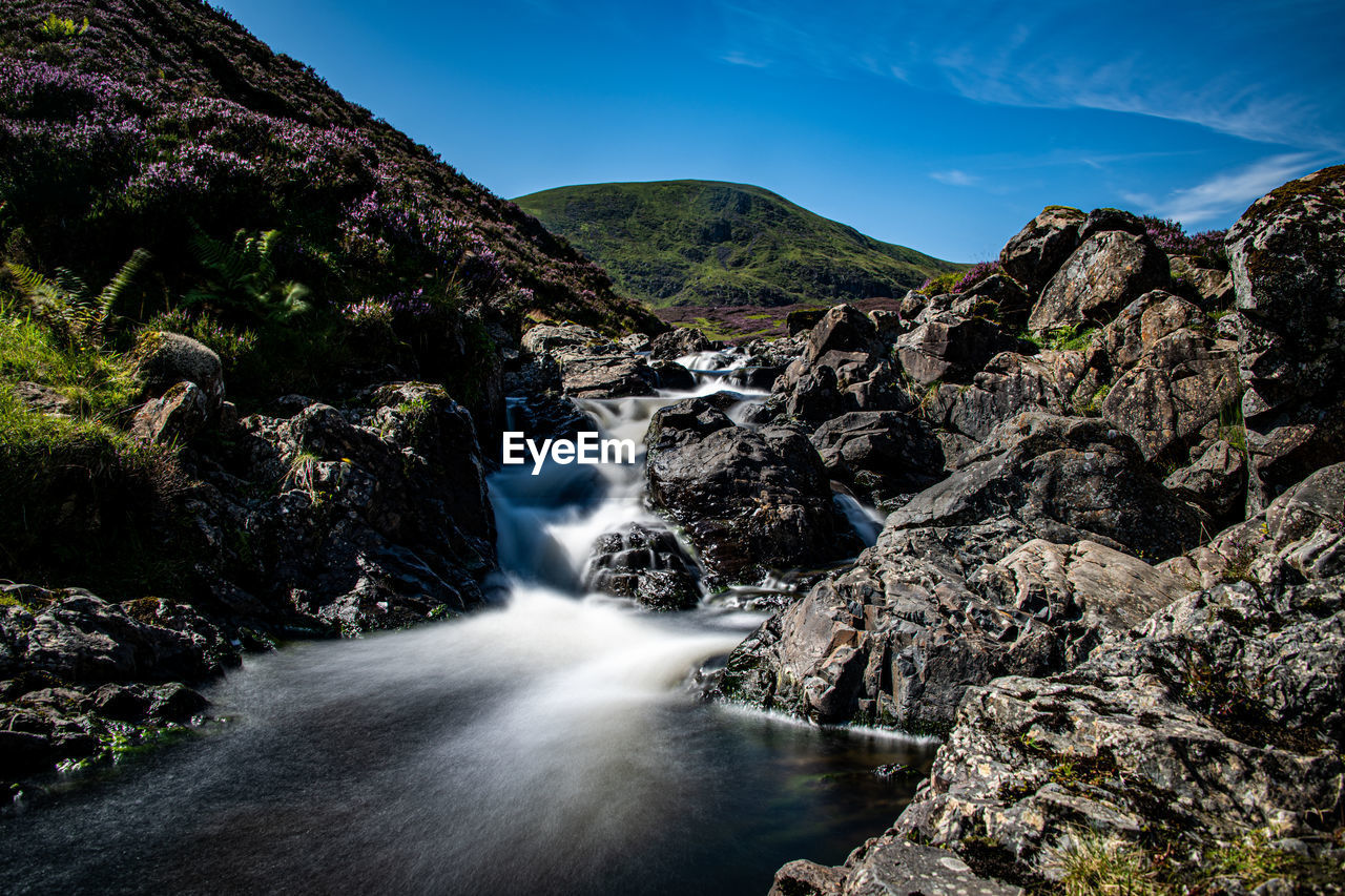 SCENIC VIEW OF WATERFALL AGAINST MOUNTAIN