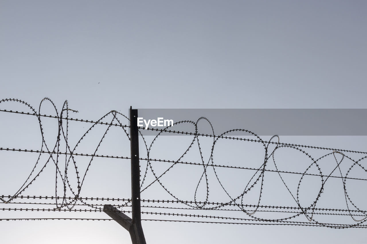 Silhouette image of barbwire fence in sunny day