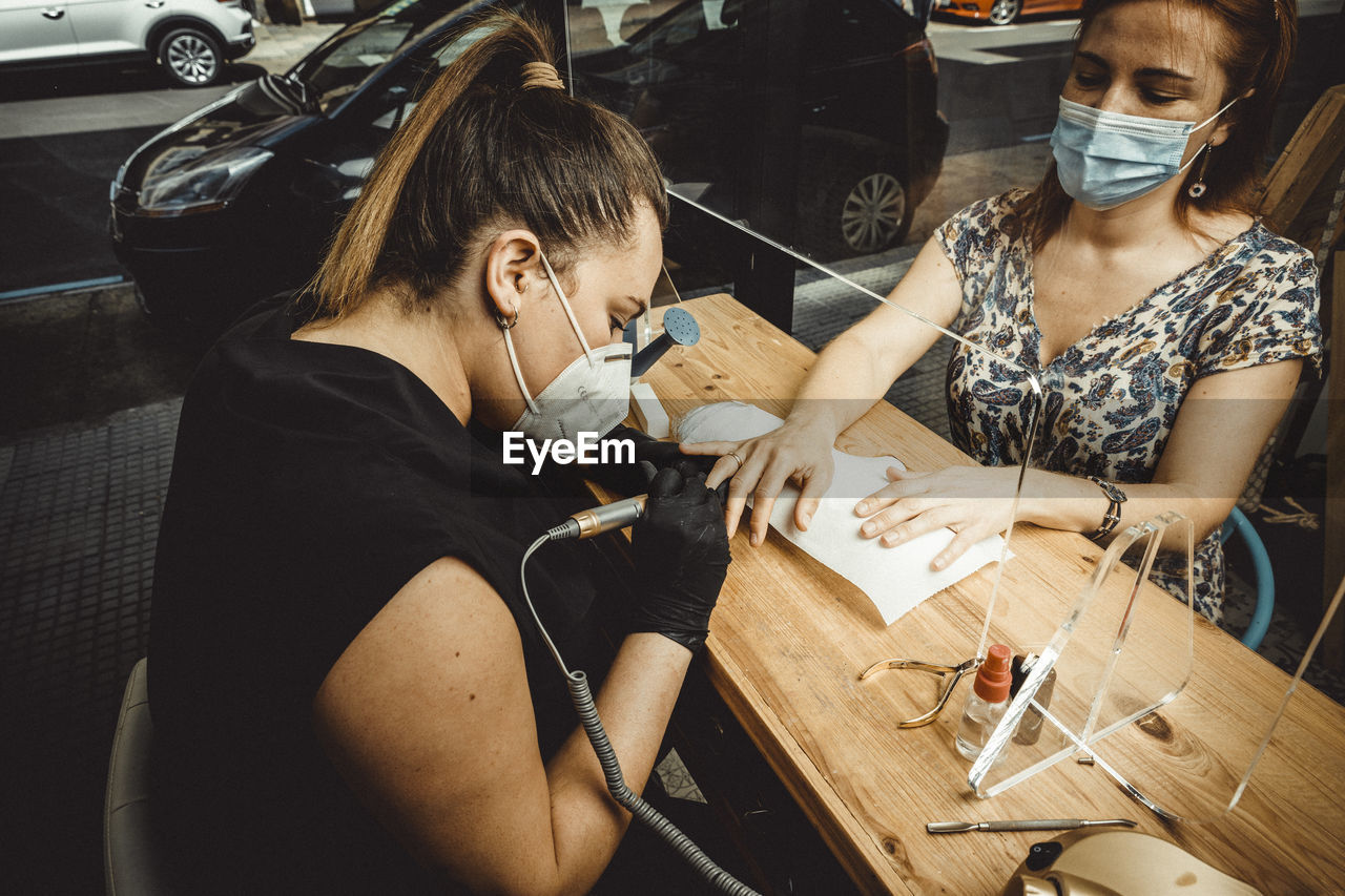 Beautician working with mask and protective screen for the virus covid