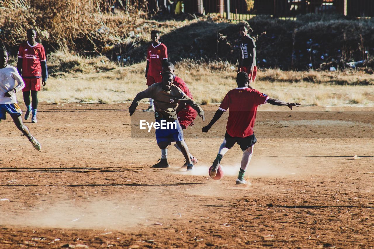 REAR VIEW OF BOYS PLAYING WITH CHILDREN RUNNING