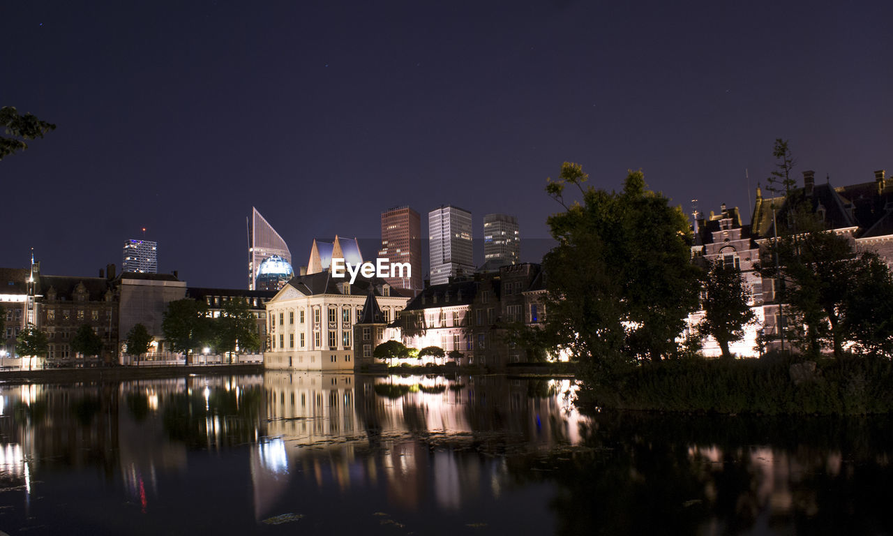 Reflection of buildings in lake at night