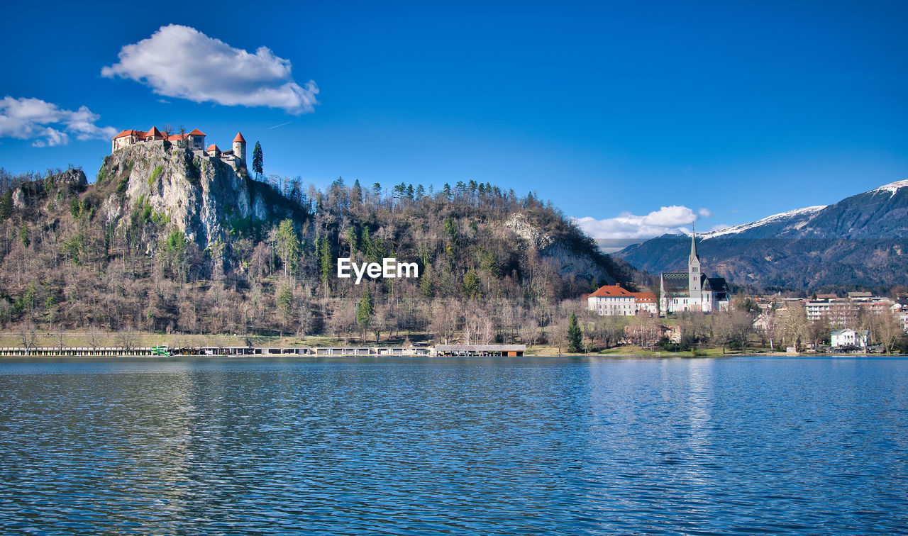 Scenic view of lake by buildings against blue sky