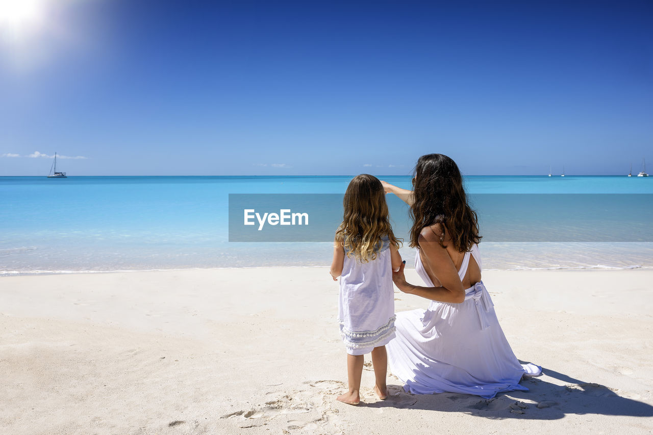 rear view of woman standing at beach against clear sky