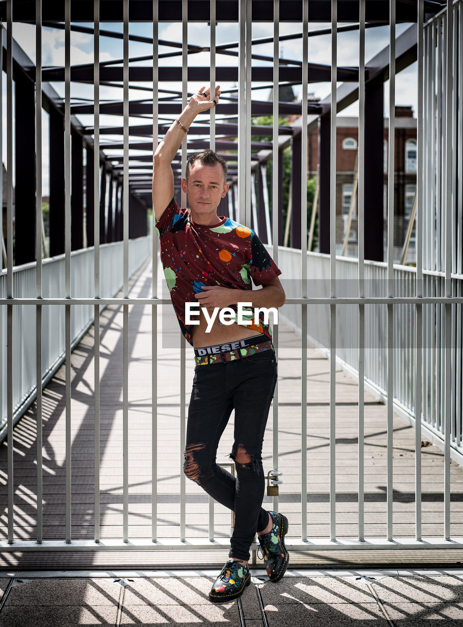 PORTRAIT OF WOMAN STANDING ON FOOTBRIDGE