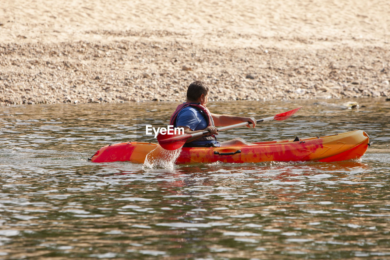 water, boat, nautical vessel, transportation, canoeing, leisure activity, kayak, nature, kayaking, vehicle, oar, men, sports equipment, one person, boating, lifestyles, adult, day, sea kayak, sports, adventure, life jacket, canoe, sitting, watercraft, outdoors, rear view, motion, sea, paddle, recreation, vacation, childhood, mode of transportation, trip, holiday, women, child, weekend activities, water sports, summer, land, waterfront, travel, person, activity