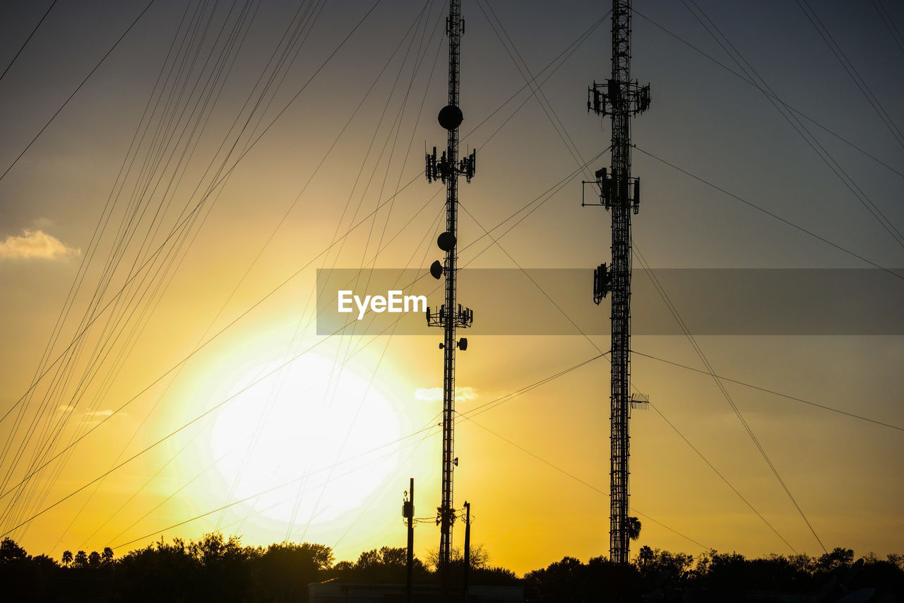SILHOUETTE ELECTRICITY PYLONS AGAINST SKY AT SUNSET