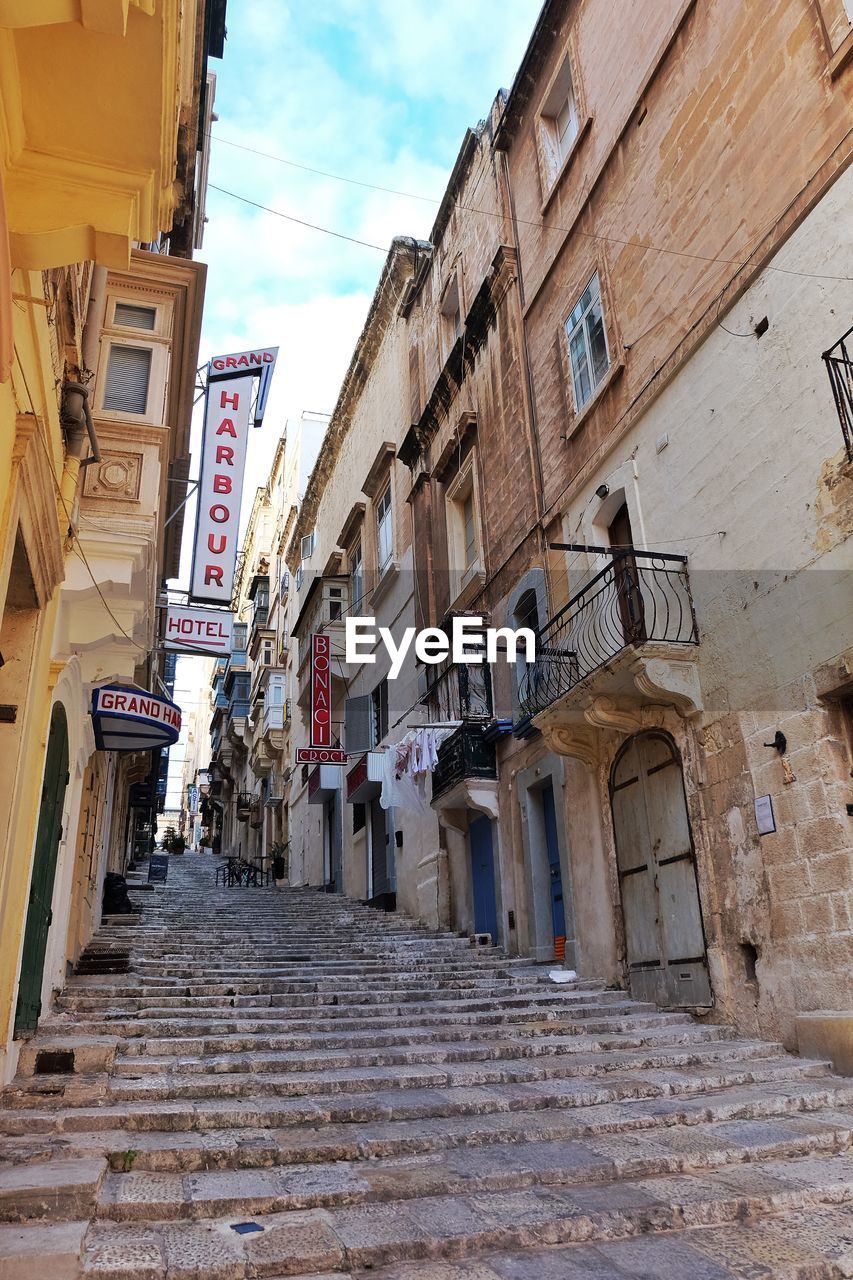 LOW ANGLE VIEW OF STAIRCASE AMIDST BUILDINGS