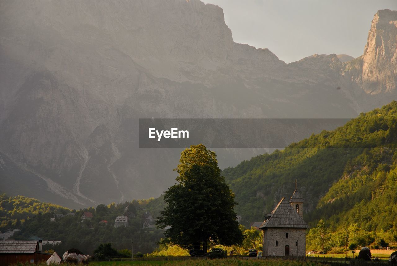 View of trees and buildings against mountain range