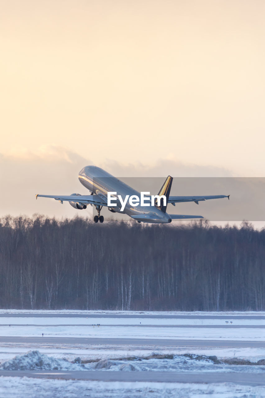 Airplane taking off during a sunset in winter time. aviation concept