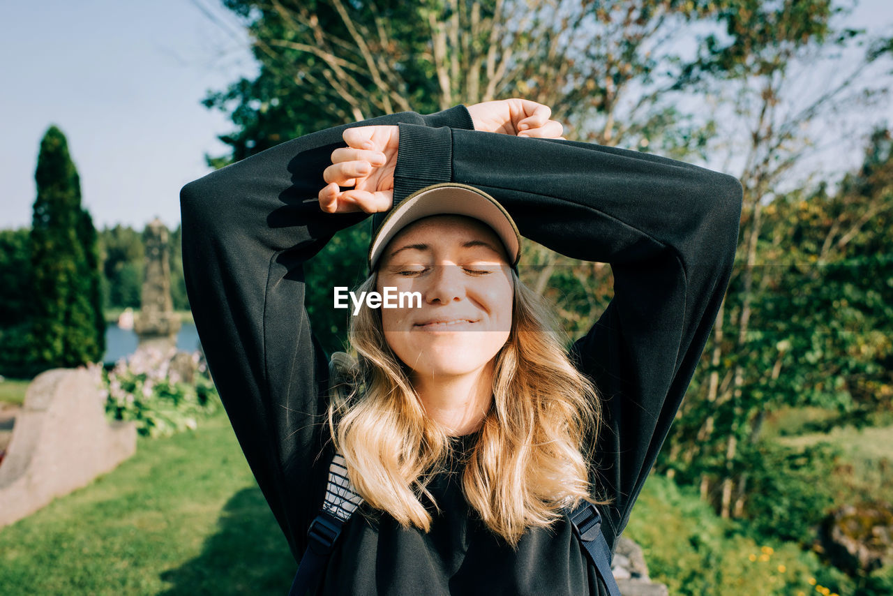 Woman sat in the countryside smiling soaking up the sunshine